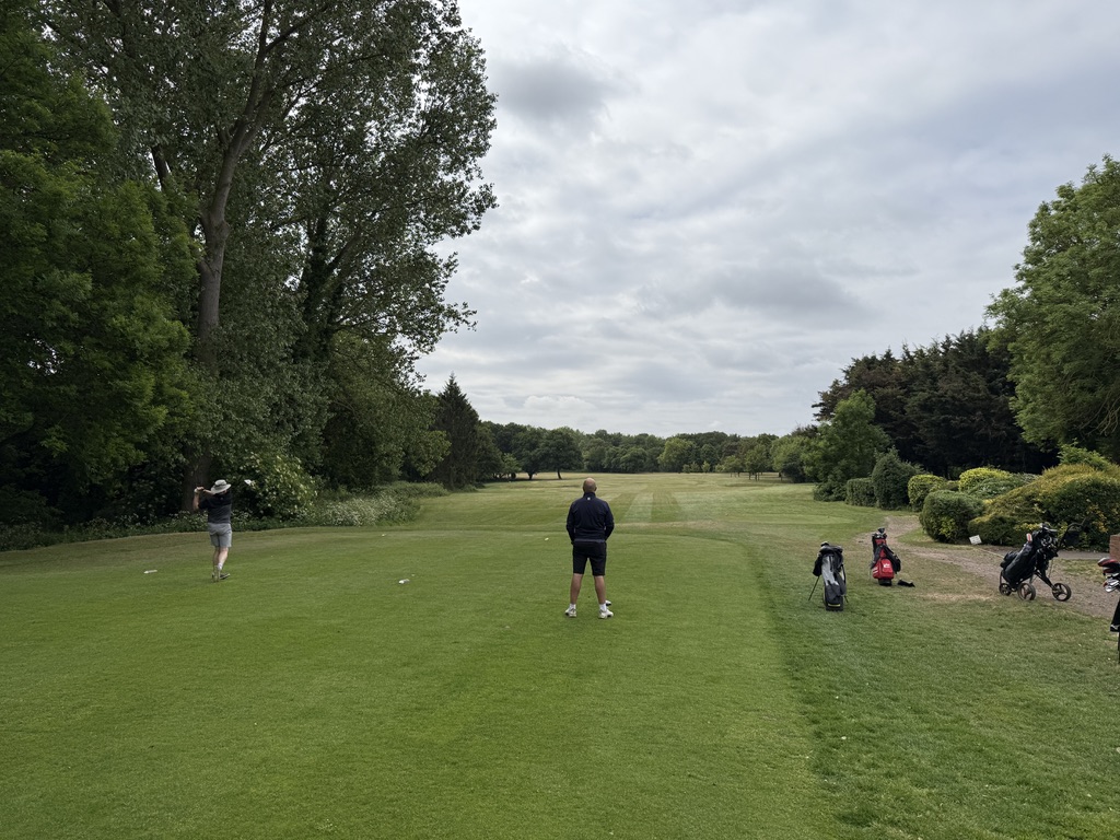 Golfers playing on the tree-lined course at West Middlesex Golf Club.